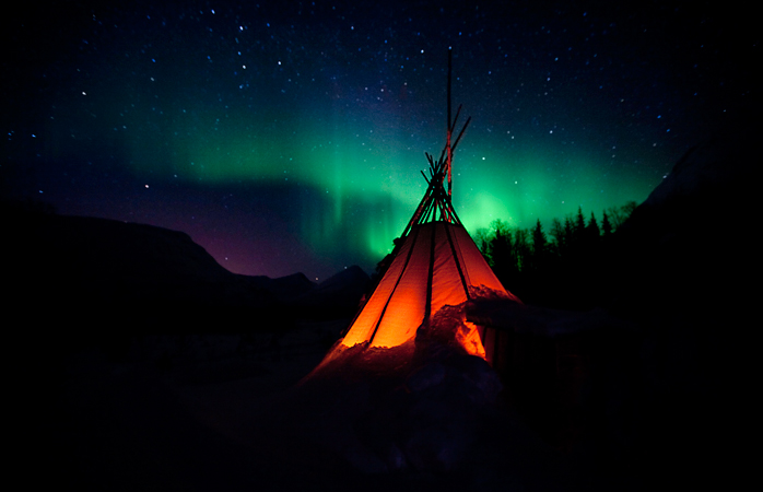 Een typisch Noorse lavvo tent onder de Aurora.