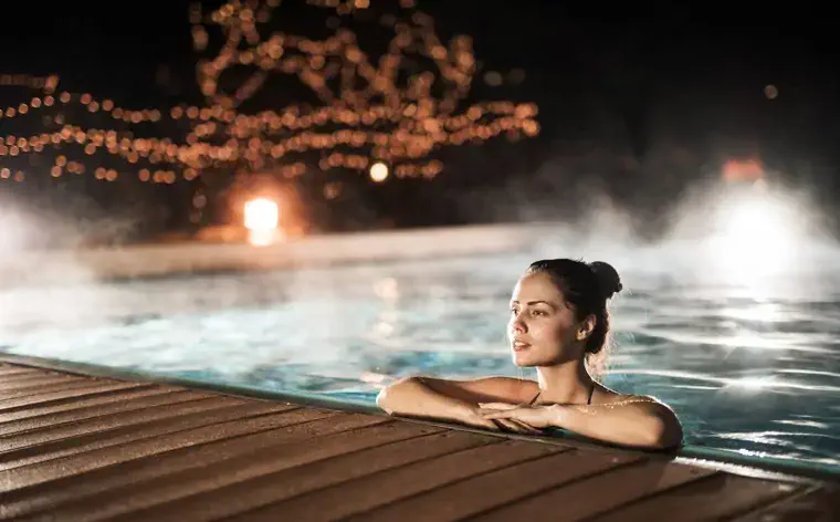 Vrouw die een de winternacht in een verwarmd zwembad doorbrengt.