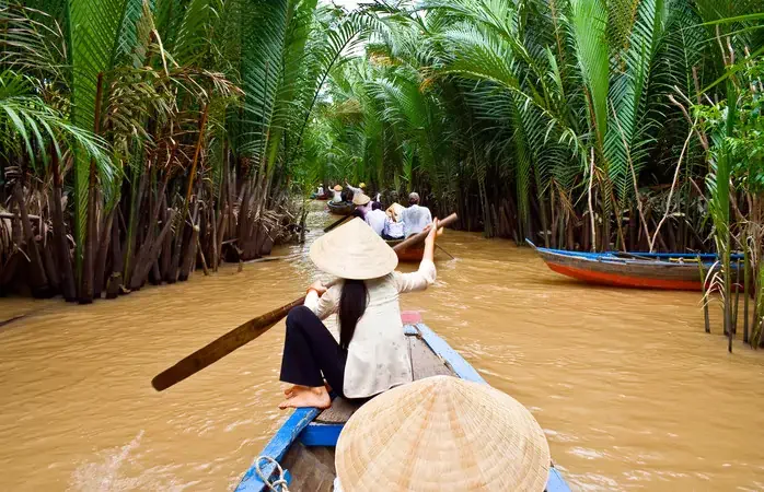 Vietnamese woman rowing a boat in Mekong River in Vietnam